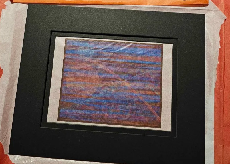 Processing piece experimentally printed on white tissue paper, framed by a black mat
